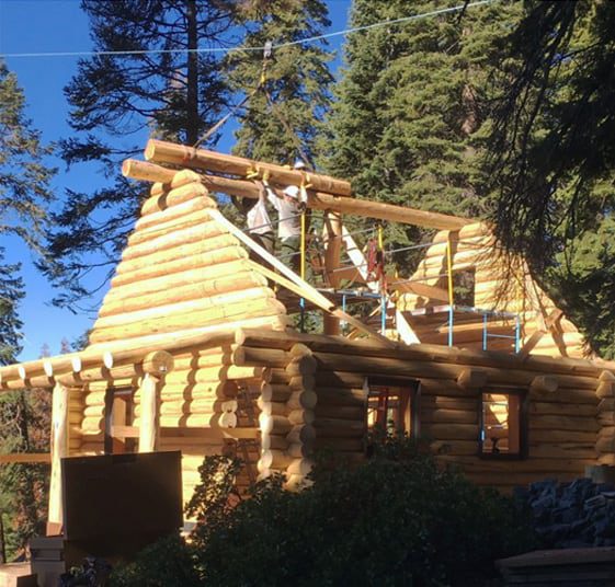 Log home being built with a man on scaffolding.