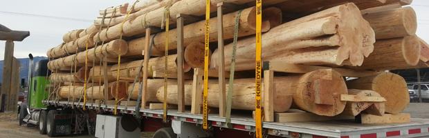 Flatbed truck loaded with logs and beams.