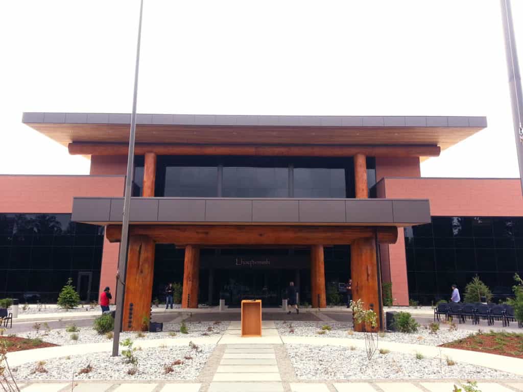 Large tribal building with wooden support beams on the exterior of building.