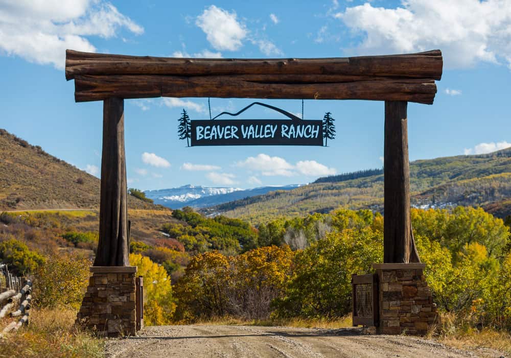 Custom log entryway to a piece of property. A sign is hanging from the large wooden beams that says, "Beaver Valley Ranch".