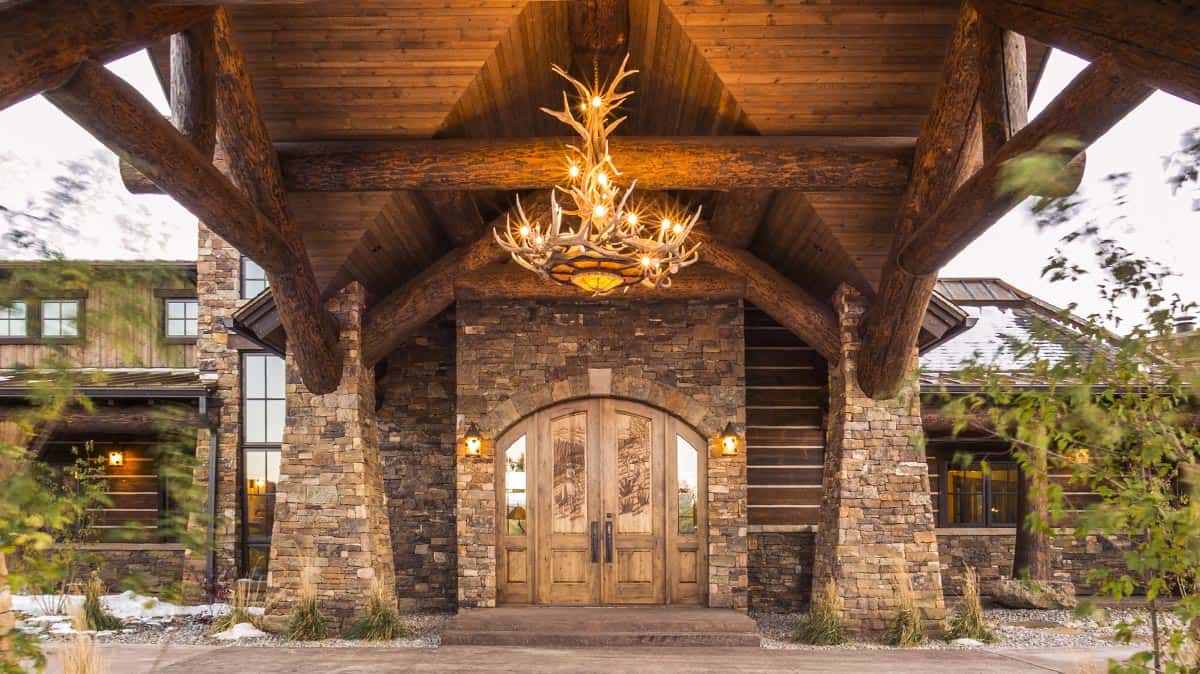Amazing portico on a custom log home with stone columns and a massive antler chandelier.