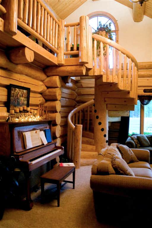 Custom built spiral wooden staircase in a home going from the living room up to a loft area.