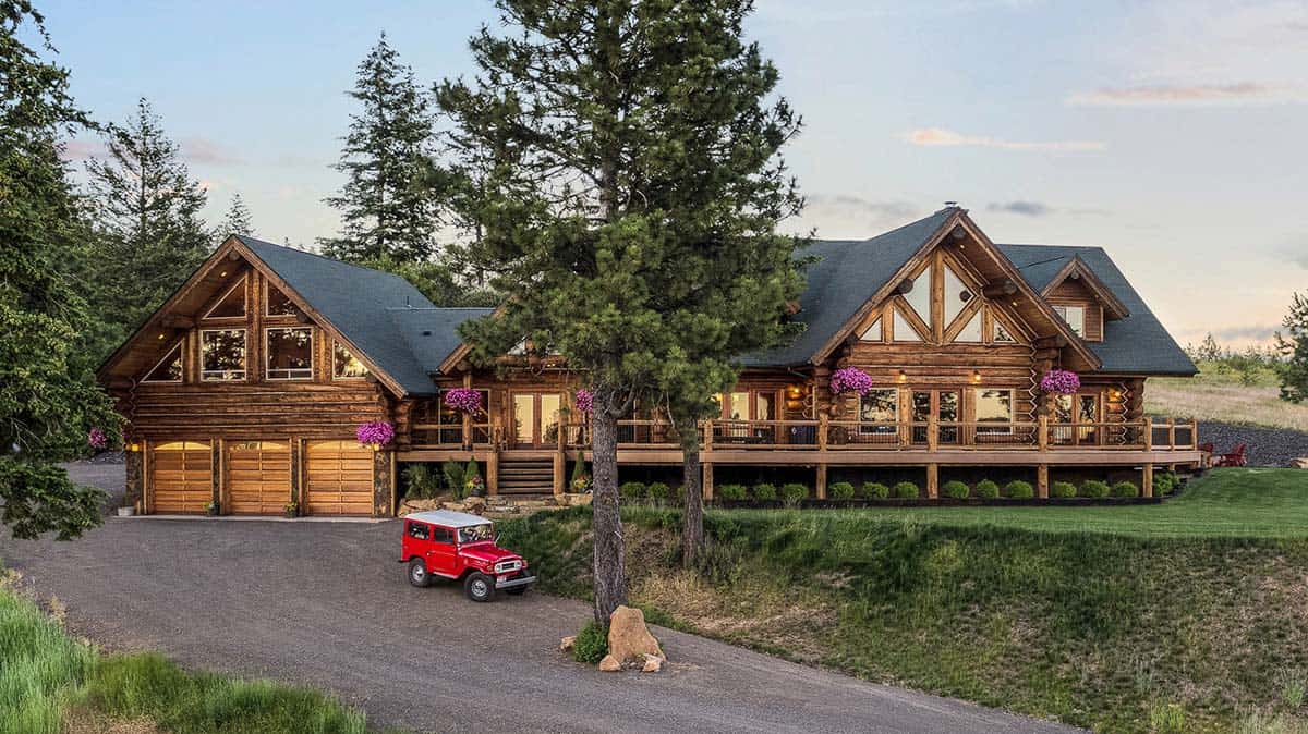 Beautiful two story log home with three car garage. Red car in the driveway.