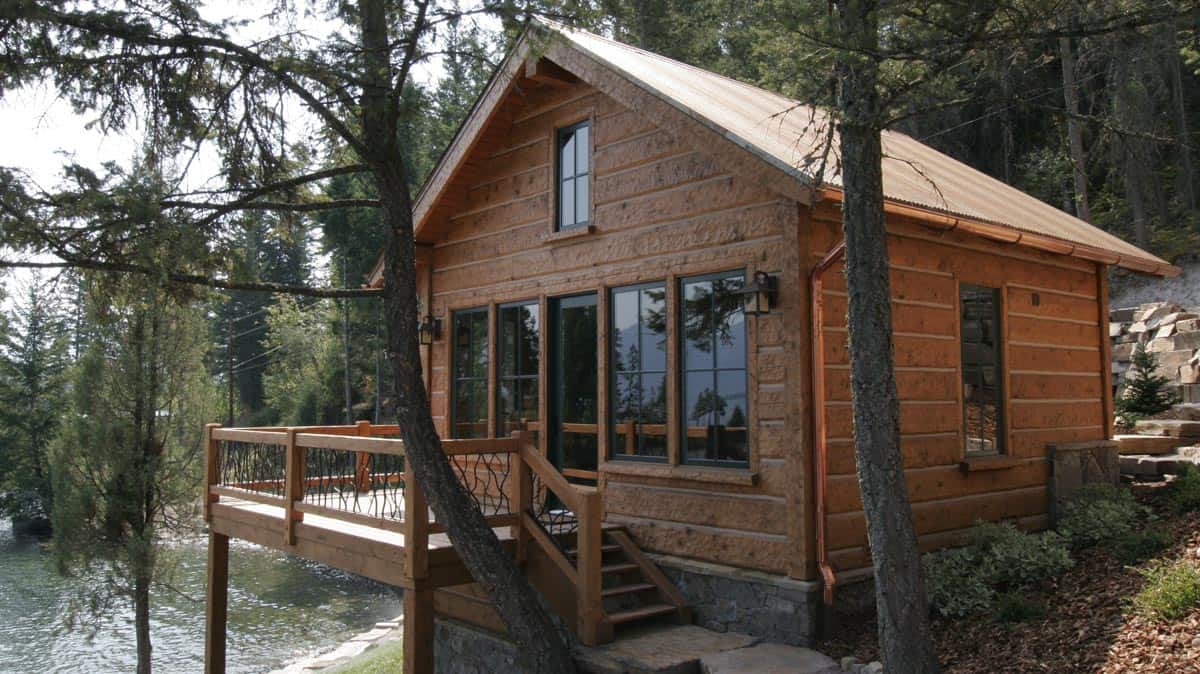 Full view of a wood sided cabin styled guest house, overlooking a lake.