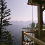 View of a mountain lake from a wooden deck with large wood beam supports.