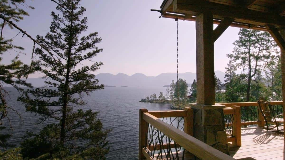 View of a mountain lake from a wooden deck with large wood beam supports.