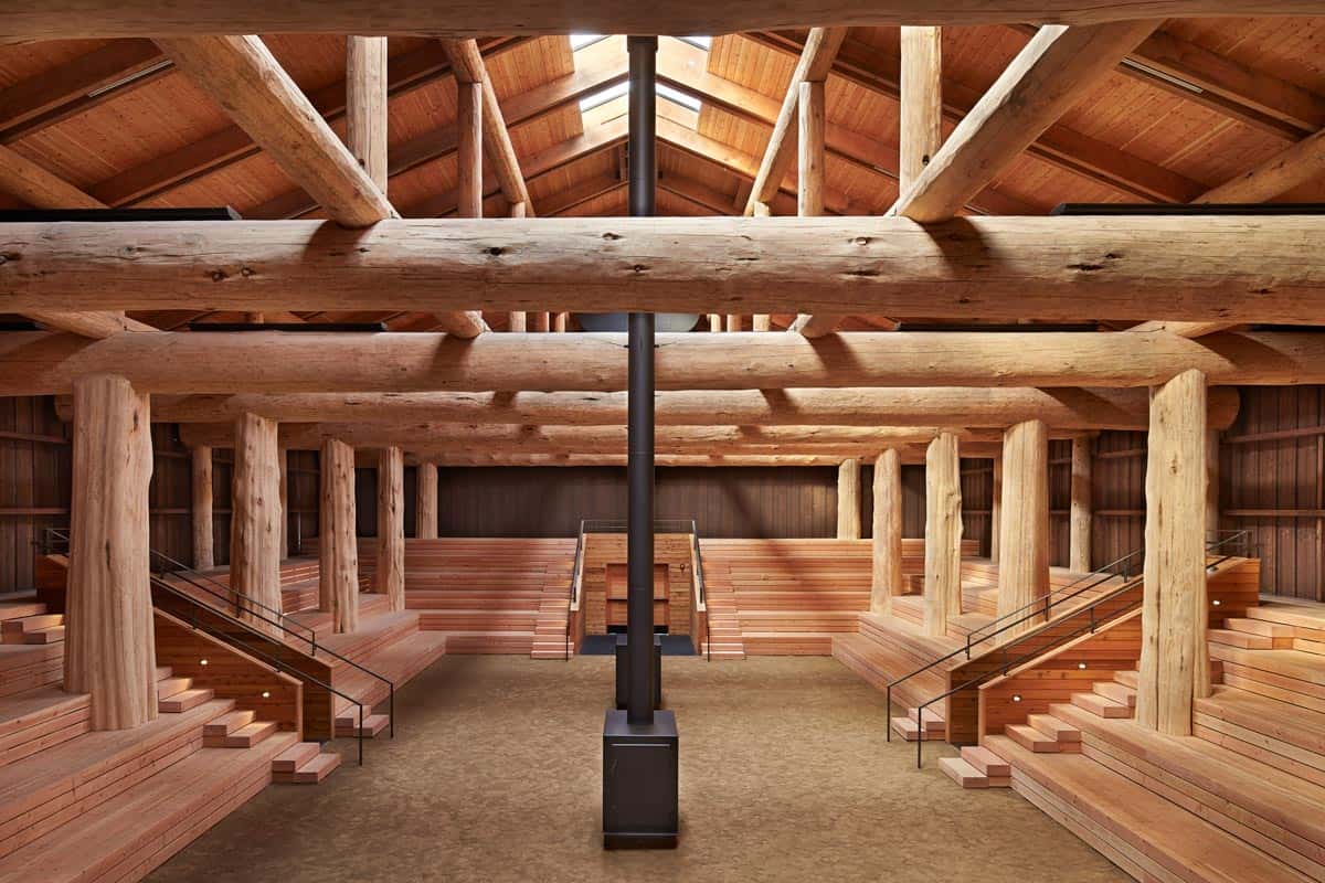 Interior view of a large commercial smokehouse with wooden beams, wooden stairs and two large smokers.