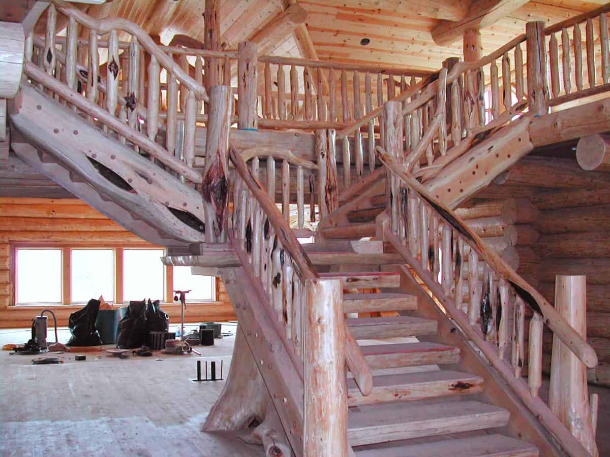 Picture of a custom built wooden staircase that has a center portion, then a landing and two side staircases from the landing to the top floor.