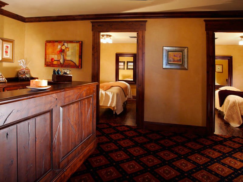 Picture from a hallway looking into two rooms with beds. A large wooden counter and wooden door frames.