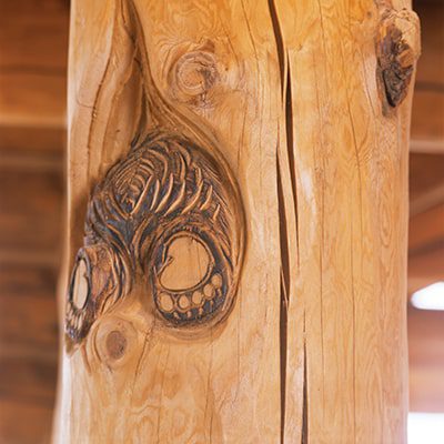 Paws and hind of a bear cub carved into wooden interior home support beam.