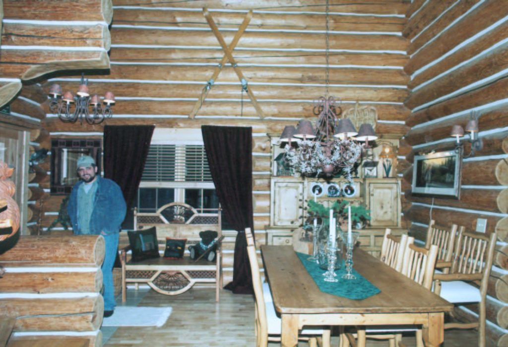 Image of Caribou Creek Founder David Byler standing in the interior of a handcrafted log home from the early '90's.