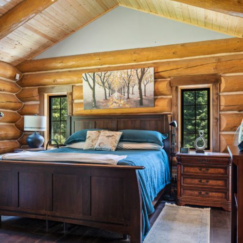 Accented with trendy teal, this log home bedroom adds a modern vibe to the classic look of log.