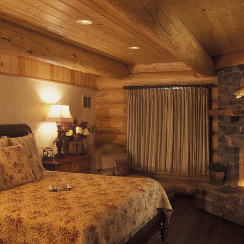 Romantic bedroom with cozy fireplace makes this log home bedroom dreamy.