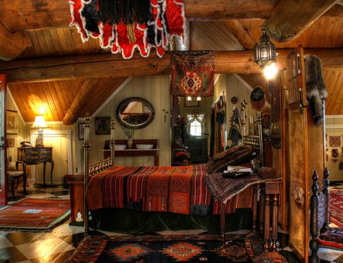Bold colors accent this log home bedroom for a rustic bohemian vibe.