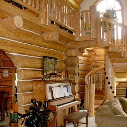 The lovely piano and spiral staircase give this chink-style log home a romantic vibe.
