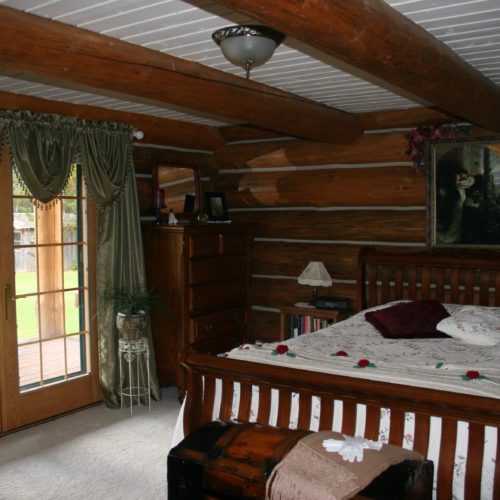 The white ceiling helps brighten this log home bedroom.