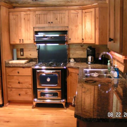 The adorable old-style copper accented stove and refrigerator make this small log cabin a country gem.