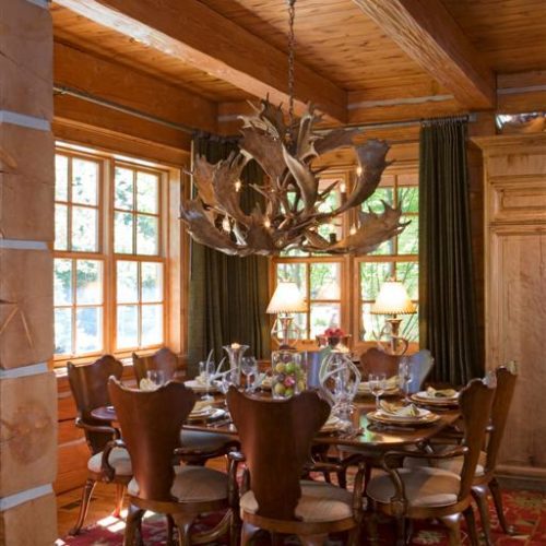 The unique chairs match the antler chandelier tying this dovetail log home dining room together.