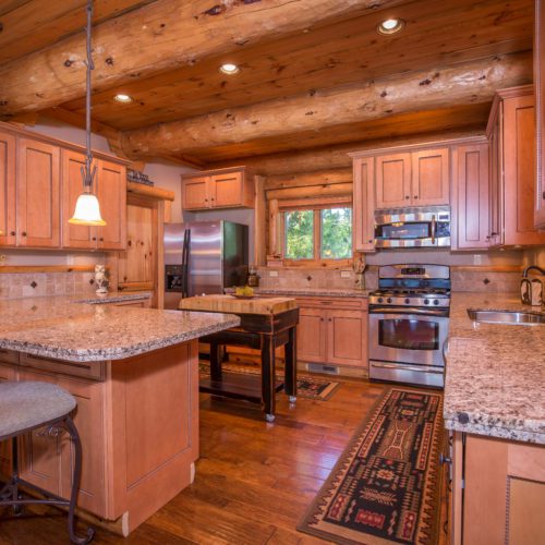 Custom cabinetry and a breakfast nook give this log home kitchen its cozy vibe.